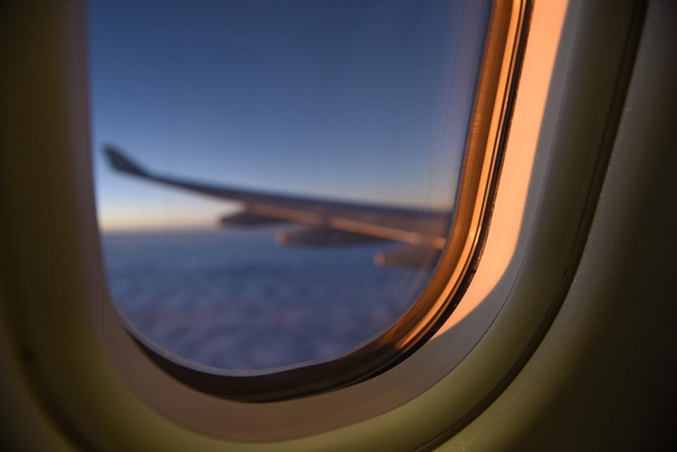 A wing seen from an airplane window at sunset