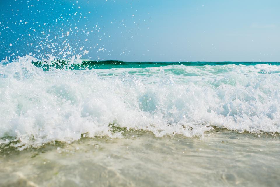 A turquoise wave breaking on white sand